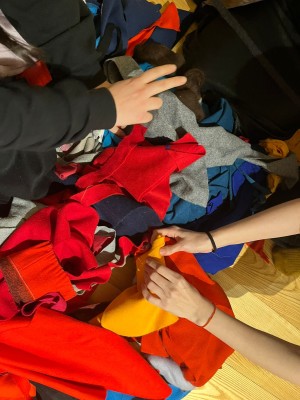 Hands by two or more people are touching colourful fabrics.